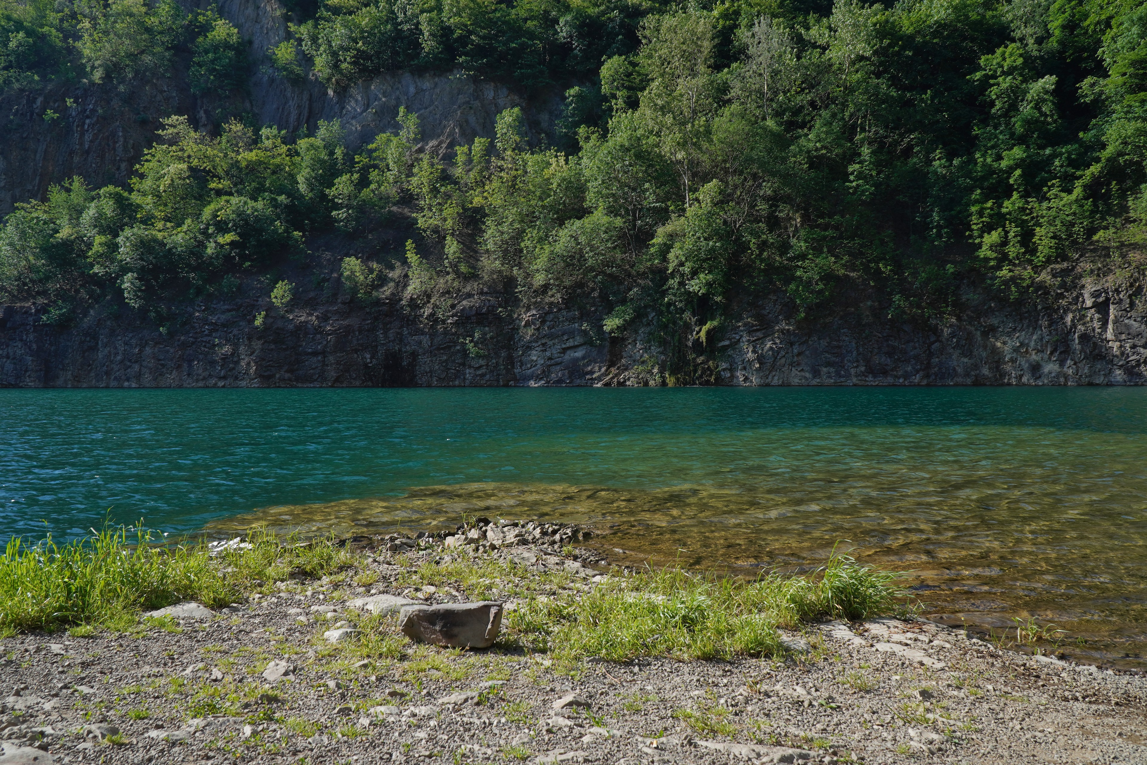 Turquoise lake surrounded by forested cliffs — travel photography poster