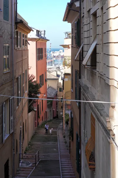Malerischer Panoramablick auf Genua, Italien, der den Hafen mit Frachtschiffen und Yachten sowie die Stadt mit charakteristischen Dächern und Kuppeln zeigt.