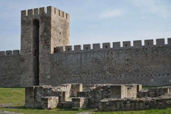 The ruins of a religious building are visible in front of the impressive stone wall and watchtower of Smederevo Fortress in Serbia.