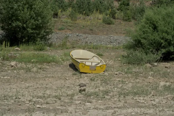 A yellow boat lies on the rocky shore of Lake Zaovine, surrounded by green vegetation, in Tara National Park, Serbia.