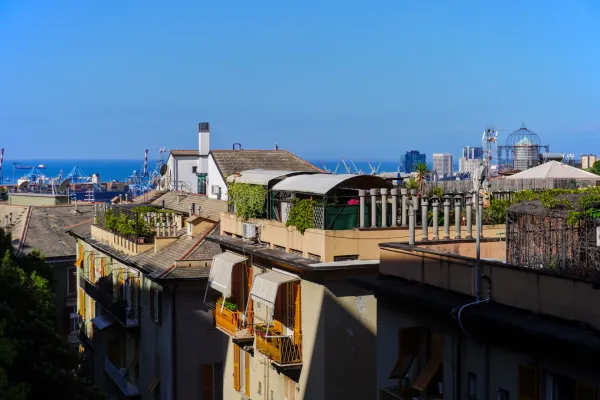 Blick über die Dächer von Genua mit Blick auf den Hafen und das Meer unter einem klaren blauen Himmel.