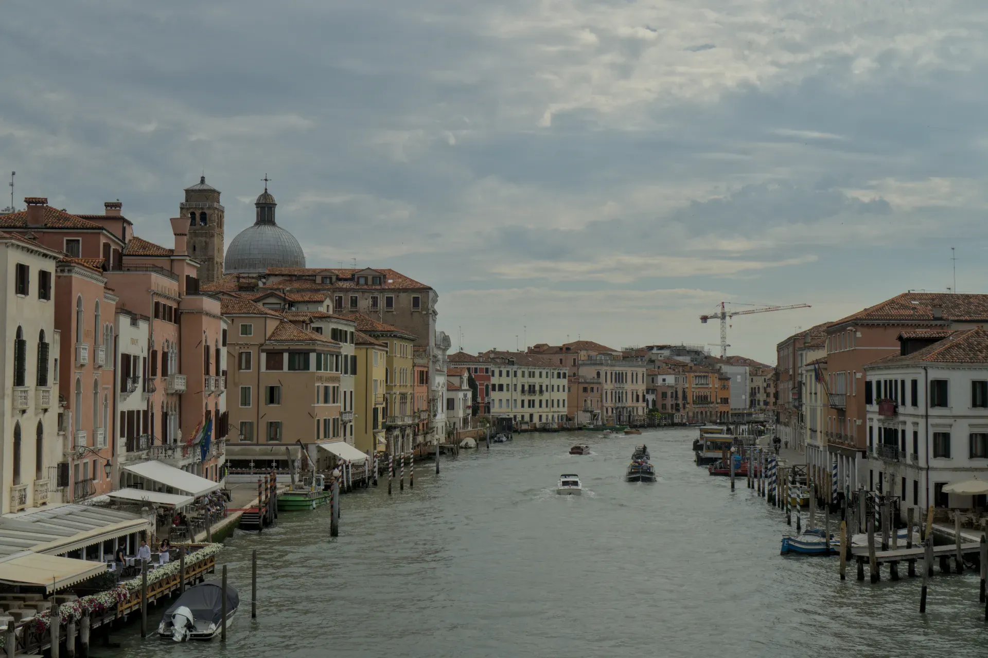 Il Canal Grande a Venezia con edifici tradizionali color pastello e barche sull'acqua, ripreso con cielo nuvoloso.