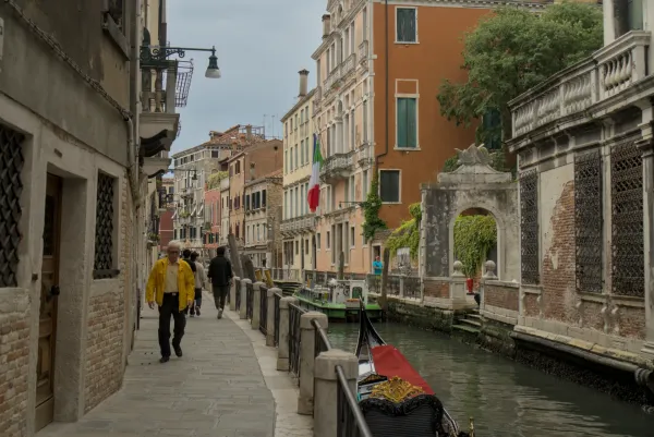 Uno stretto vicolo a Venezia conduce a un canale, fiancheggiato da edifici storici e una gondola.