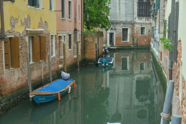 Ein malerischer Kanal in Venedig, mit traditionellen Booten und historischen Gebäuden, die sich im Wasser spiegeln.