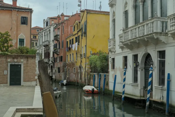 Ein ruhiger venezianischer Kanal mit traditionellen bunten Häusern und reflektierenden Wasserflächen.