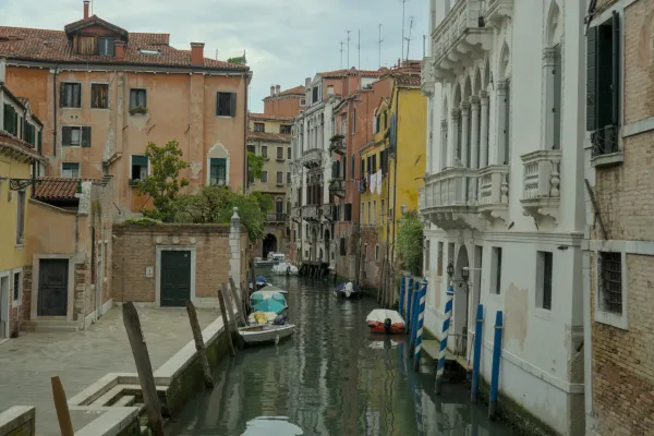 Ein schmaler Kanal in Venedig, gesäumt von historischen Gebäuden und mit mehreren Booten, die im Wasser liegen.