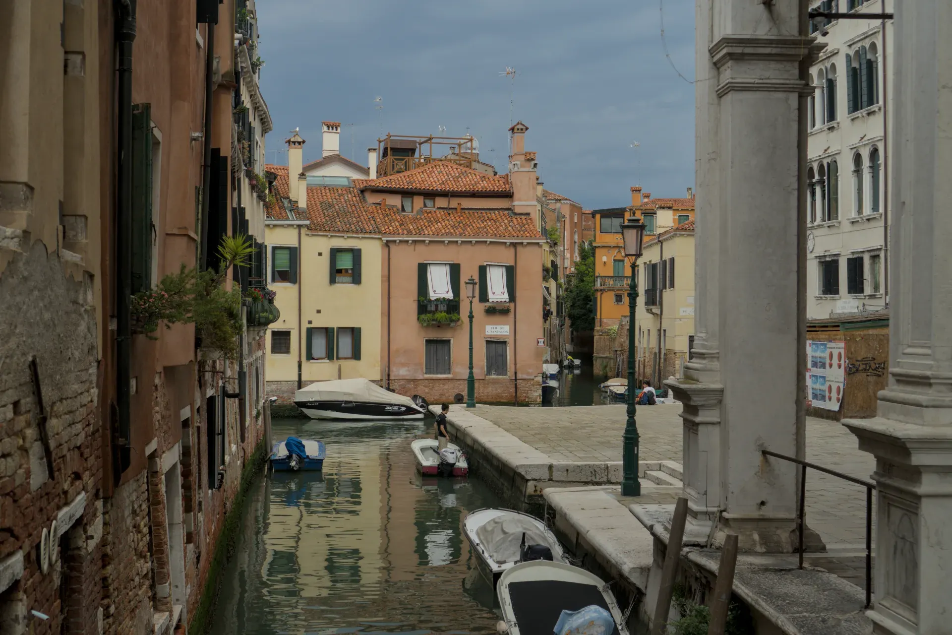 Un canale di Venezia con varie barche, circondato da edifici storici colorati e un cielo nuvoloso.