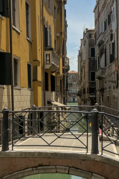 Ein venezianischer Kanal mit einer Bogenbrücke, umgeben von alten, farbigen Gebäuden und klarem Himmel.