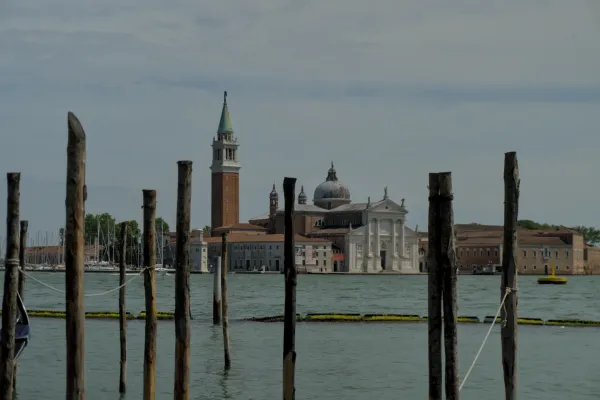 Die Kirche San Giorgio Maggiore in Venedig, Italien, mit ihrem markanten Turm, gesehen über das Wasser von den Holzpfählen im Vordergrund.