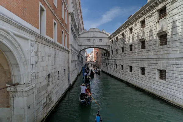 Gondole scendono lungo un canale a Venezia, Italia, passando sotto un ponte storico.