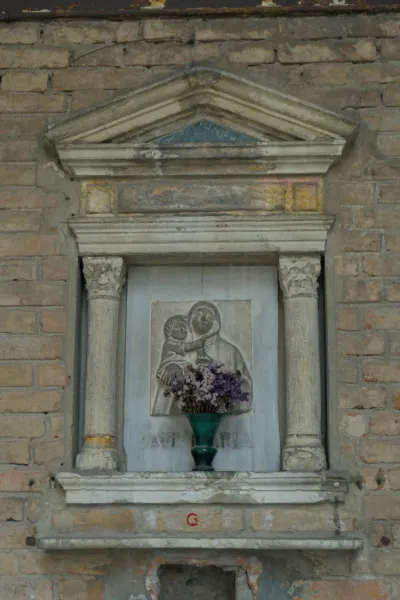 Religiöse Skulptur von Madonna und Kind mit Blumen in einer steinernen Nische, geeignet für Wanddekorationen.