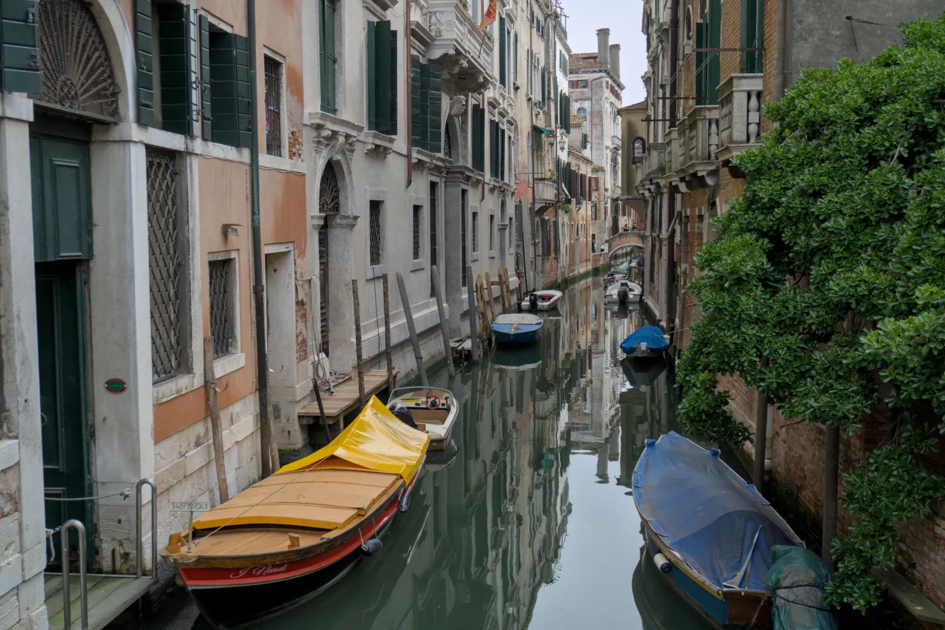 A narrow canal in Venice, lined with historic buildings and sleeping boats, an ideal artwork for interiors.