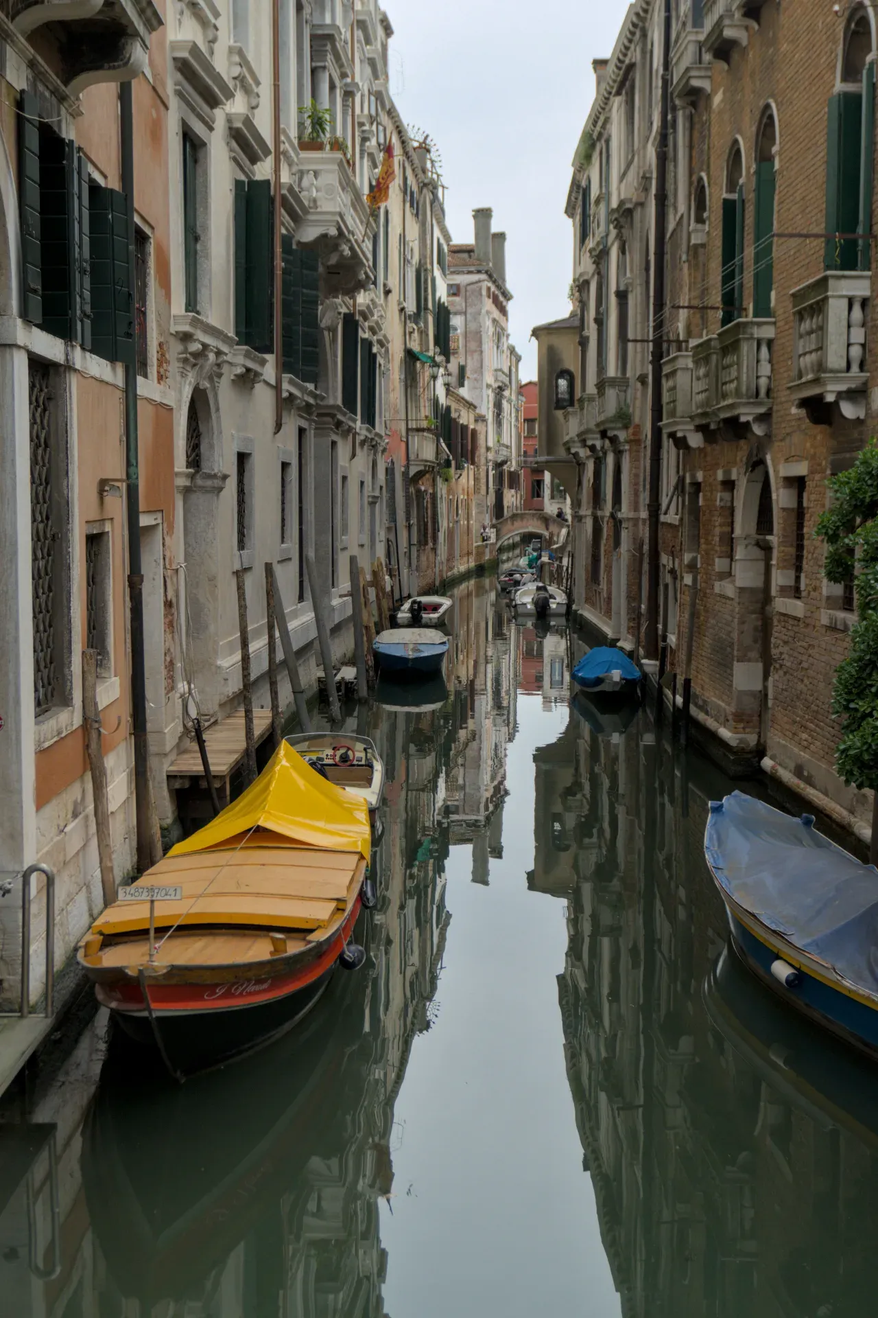 Uno stretto canale a Venezia con barche ed edifici riflessi, perfetto per l'arte da parete.
