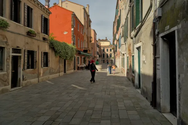 Fine Art Fotografie einer engen Gasse in Venedig mit pastellfarbenen Gebäuden und gepflastertem Boden.