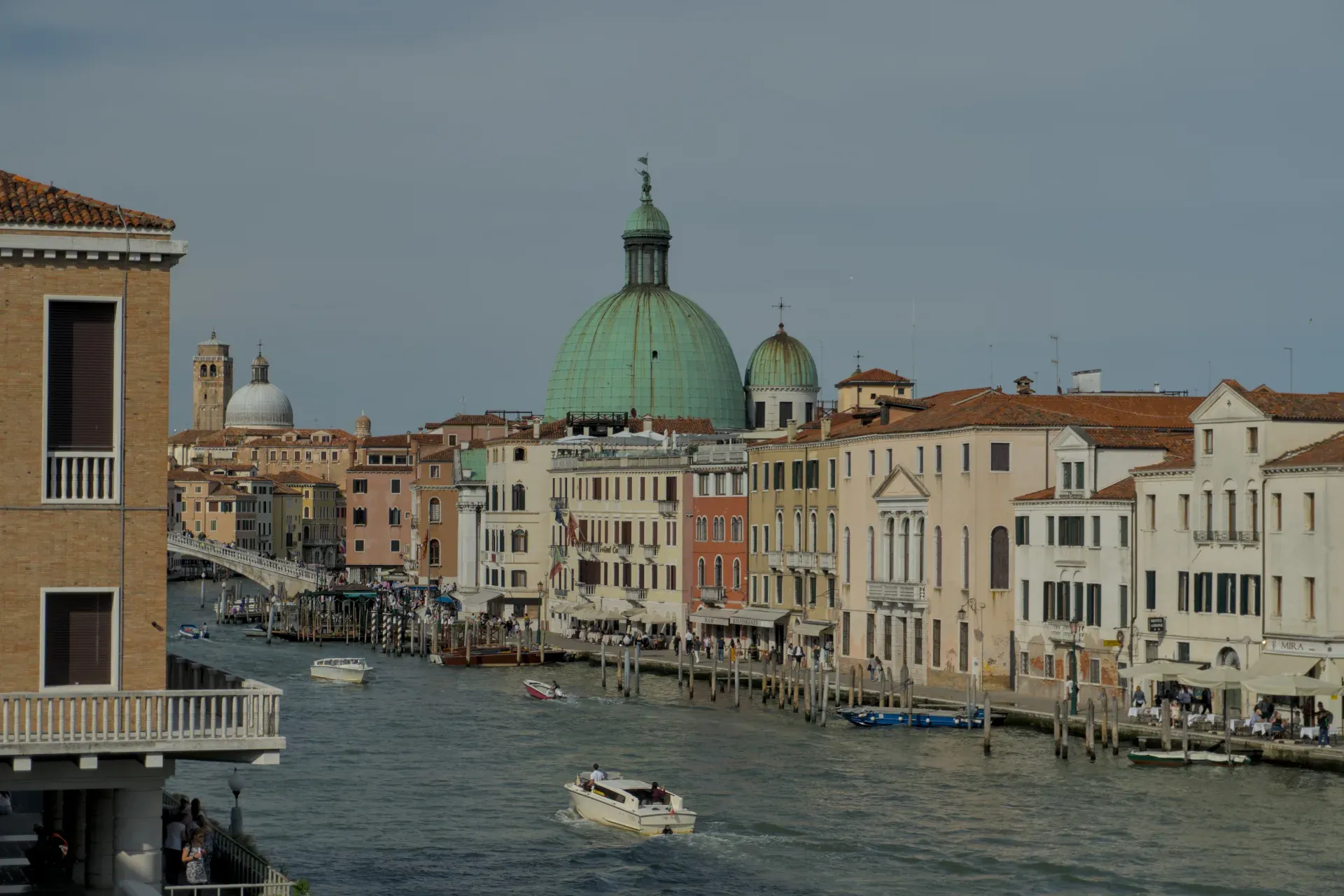 Fotografía de paisaje del Gran Canal de Venecia, Italia, con edificios tradicionales y una prominente cúpula verde al fondo.