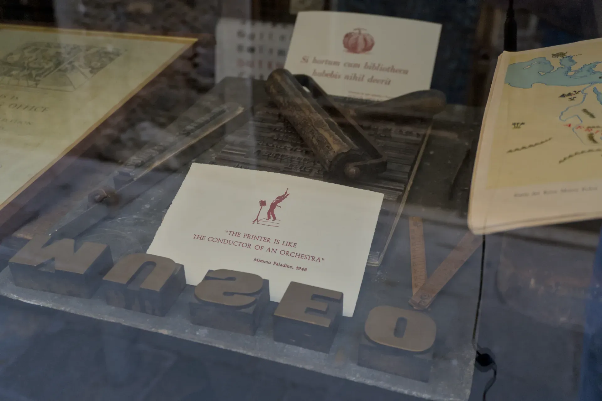 Antichi manufatti di stamperia a Venezia, comprese lettere di piombo e uno strumento di stampa, esposti dietro vetro.