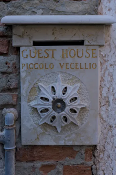 Insegna Guest House Piccolo Vecellio con scritta dorata su marmo, Venezia.