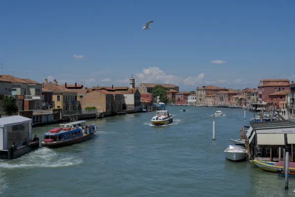 Vista di un canale sull'isola di Murano a Venezia con barche ed edifici tradizionali.
