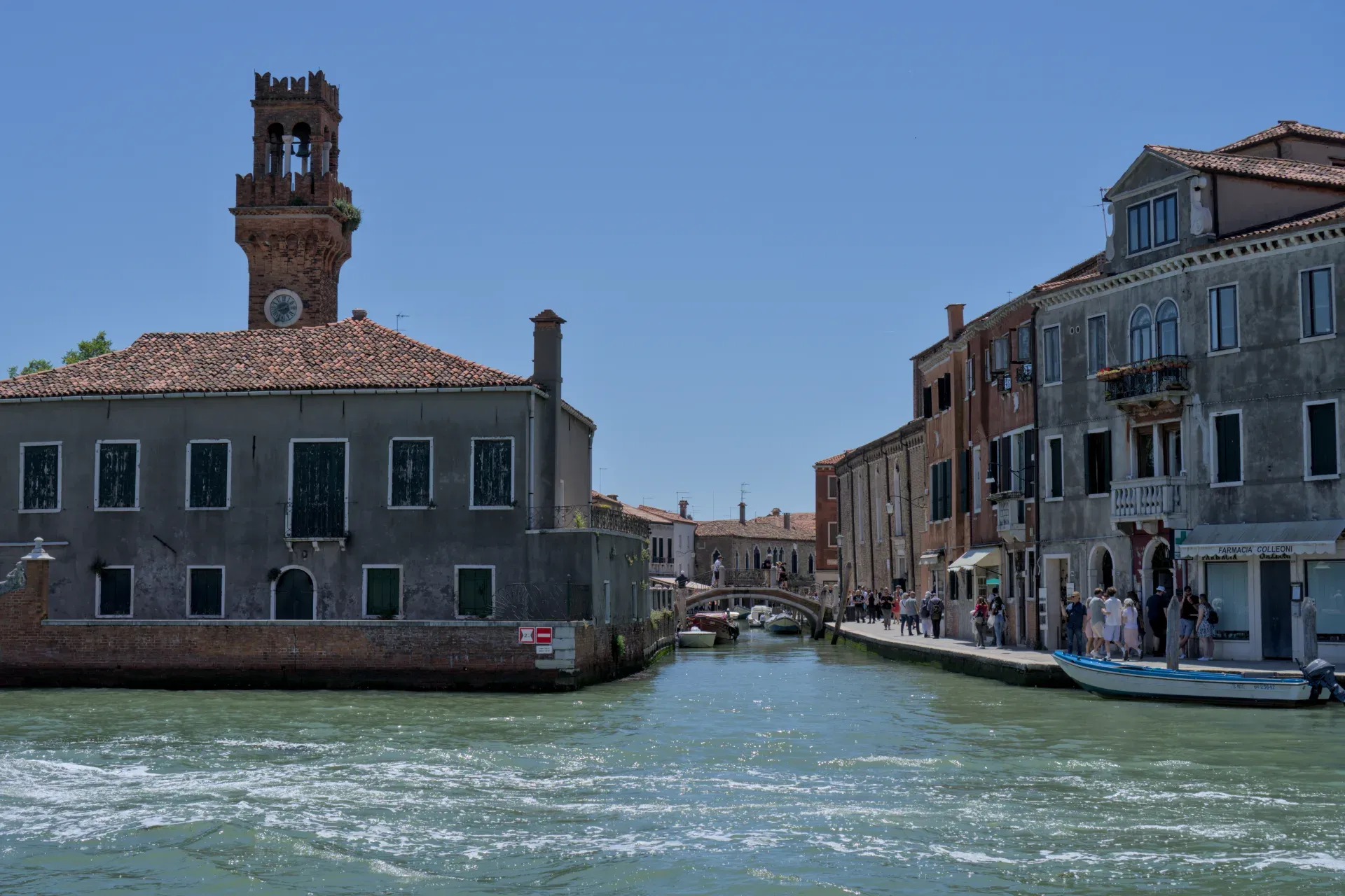 Ein Kanal auf der Insel Murano in Venedig mit einem alten Ziegelturm und historischen Gebäuden.