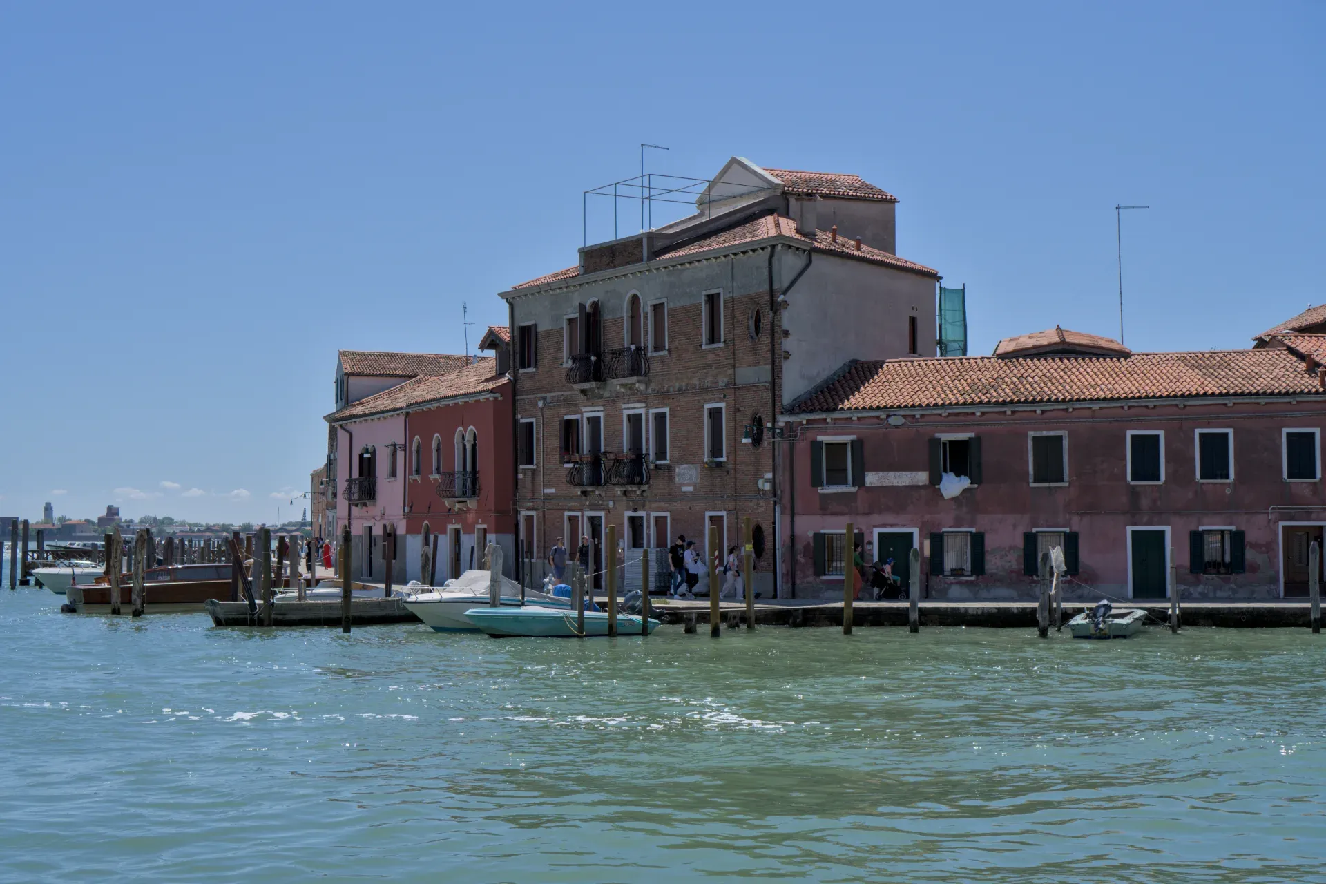 Case e barche colorate sul molo dell'isola di Murano, Venezia, alla luce del giorno.