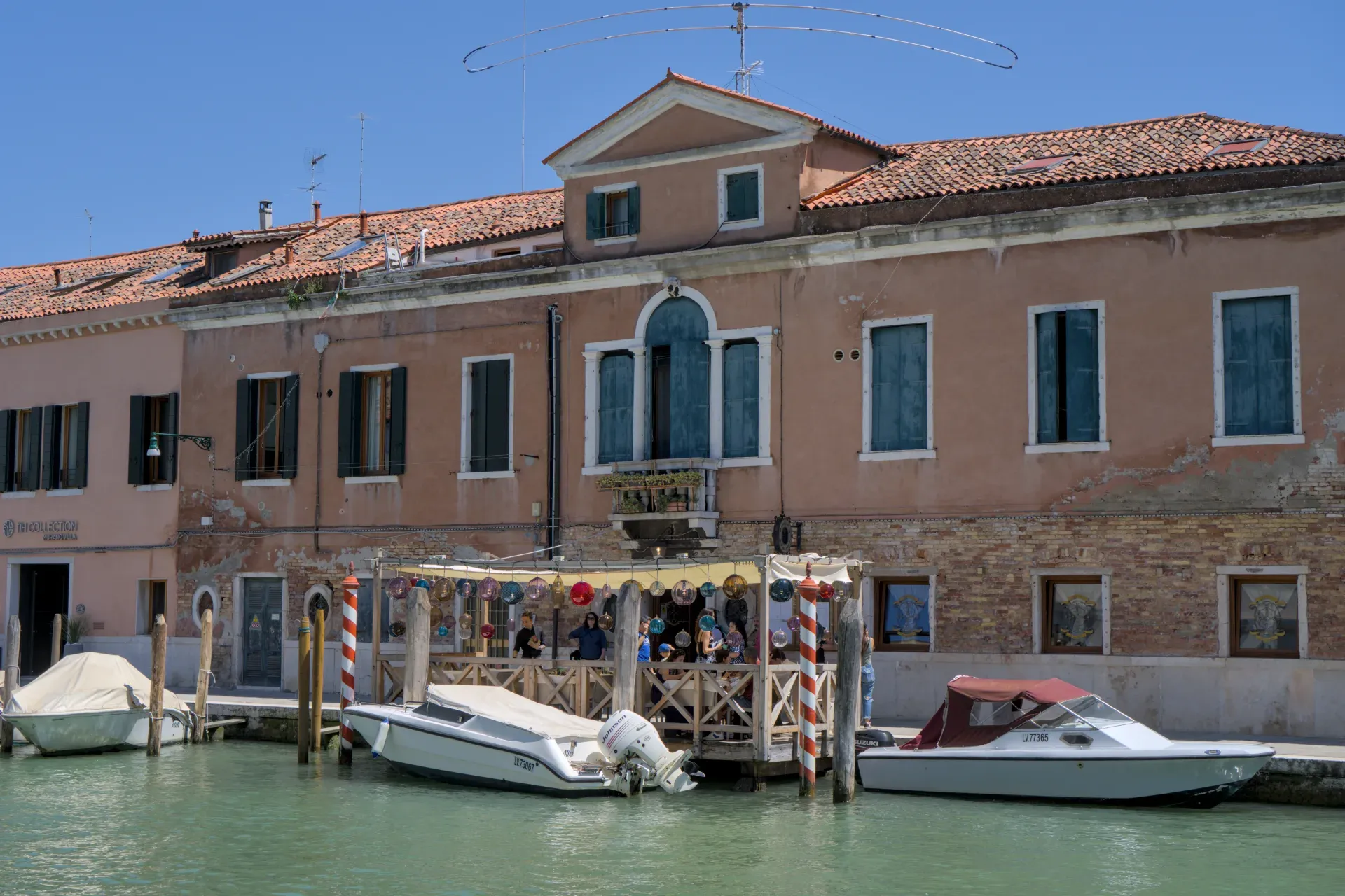 La isla de Murano con sus canales y barcas, rodeada de edificios venecianos tradicionales.