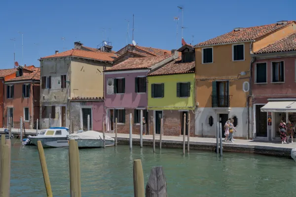 Farbenfrohe Häuser am Kanal der Insel Murano, Venedig, mit einem Boot am Kai.
