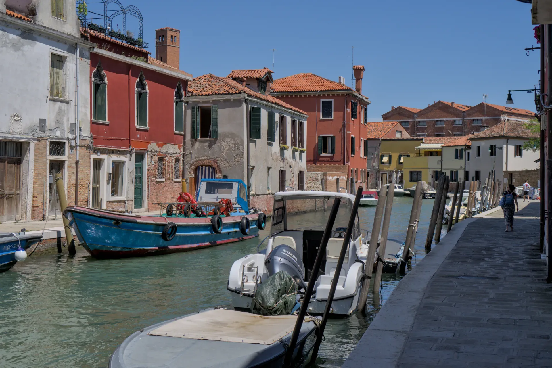 Un pintoresco canal en la isla de Murano en Venecia con barcos tradicionales y casas coloridas.
