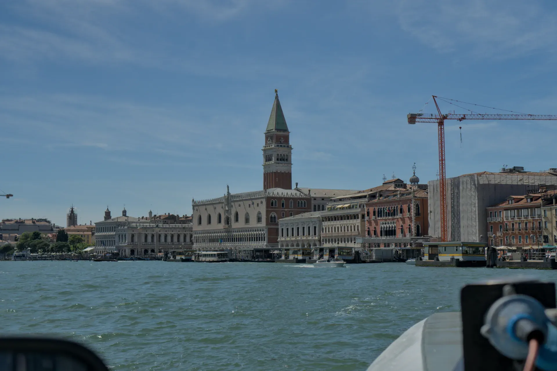 Costa veneziana con palazzi storici e acqua turchese al sole.