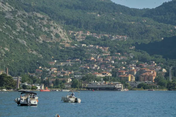 View of the Bay of Kotor with boats on the water and a city nestled against green mountain slopes.