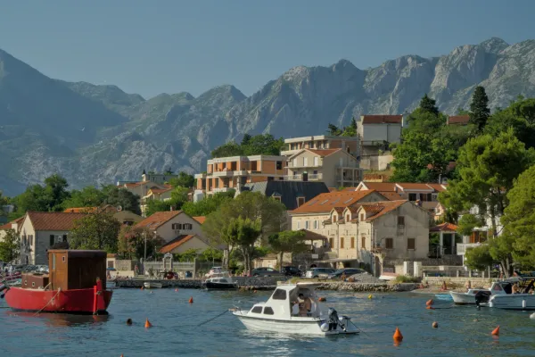 Picturesque view of the Bay of Kotor with charming houses, boats, and majestic mountains in the background, depicting a scene of Dobro.