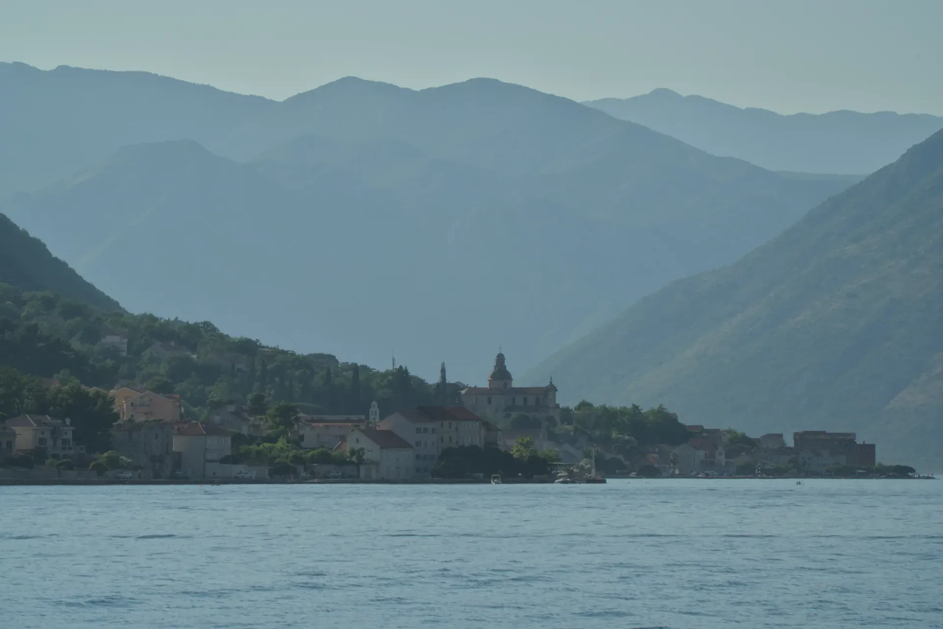 Coast of Kotor with a town and mountains in the background, captured from a water perspective.