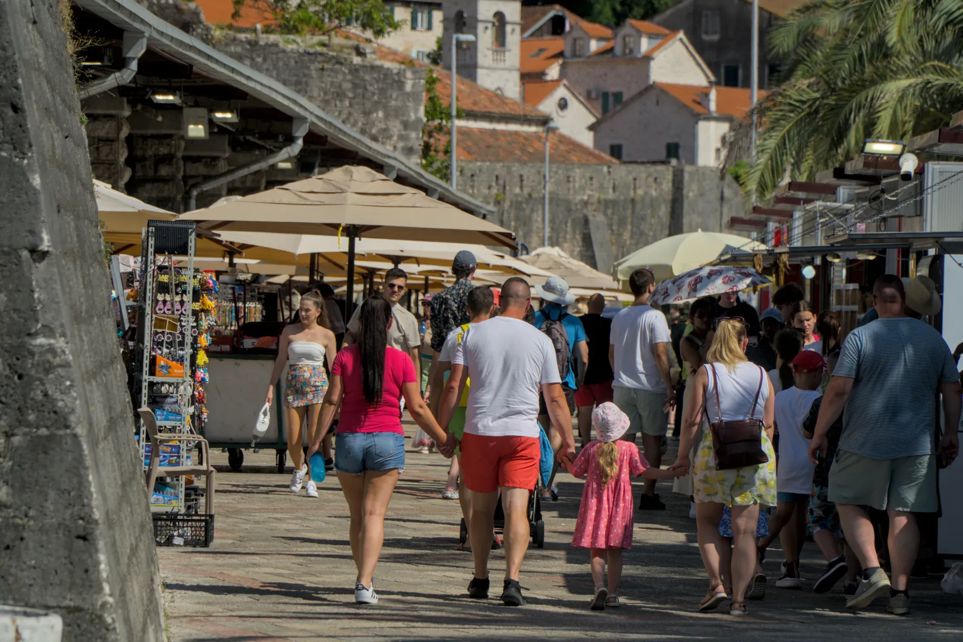 Persone che passeggiano davanti alle bancarelle del mercato a Kotor, Montenegro, vicino al centro storico.