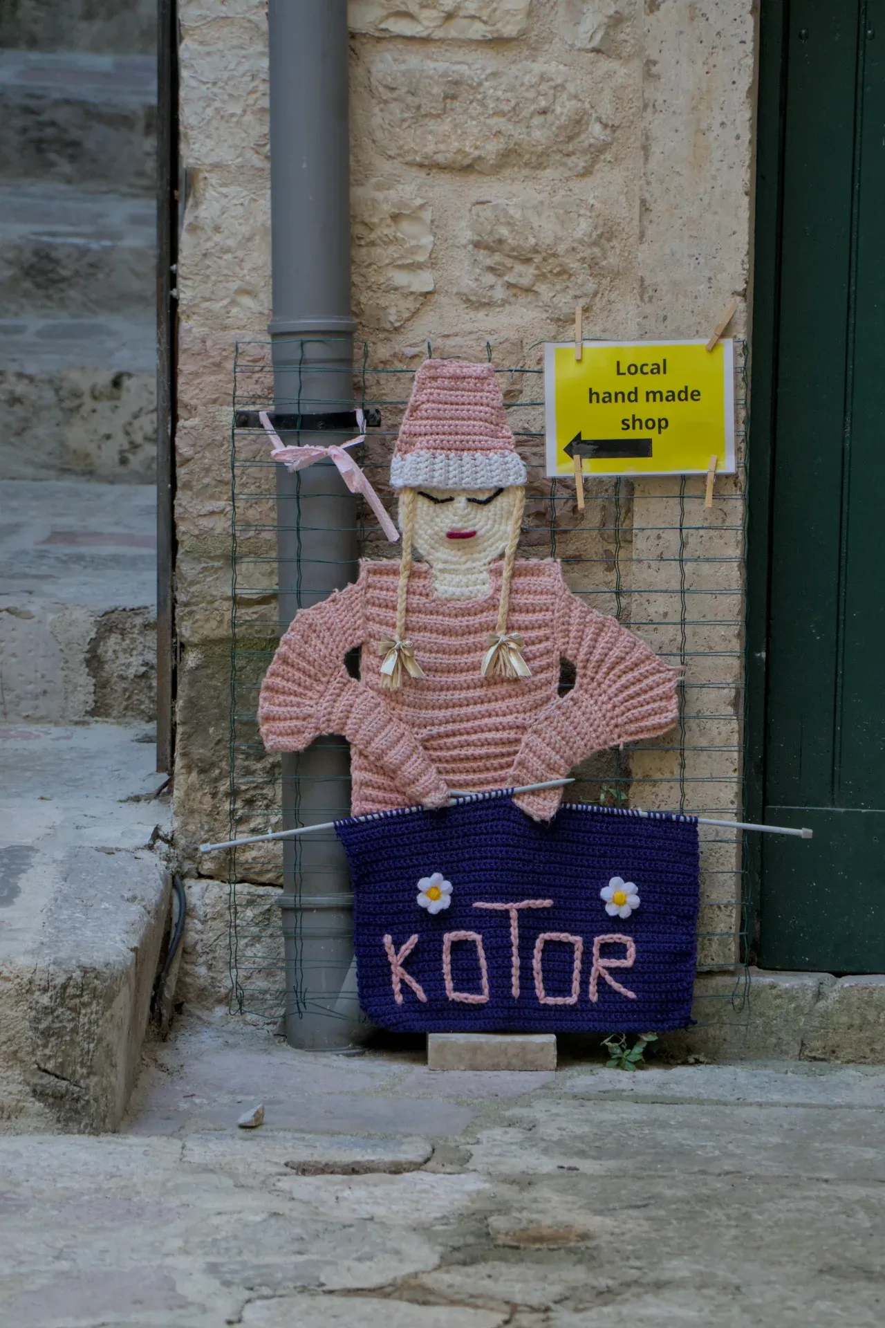 Handmade knitted sign reading 'Kotor' and 'Local hand made shop' in Montenegro.