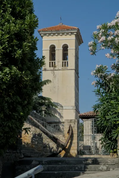 An old bell tower rises above a stone staircase with a large rusty anchor in Herceg Novi, Montenegro.
