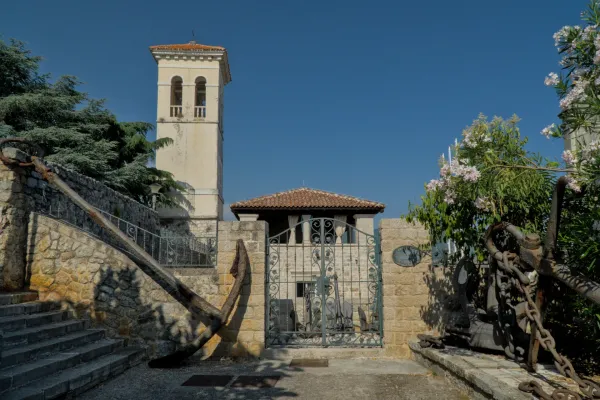 An old, rusty anchor lies in front of a stone staircase, next to it a slender bell tower.