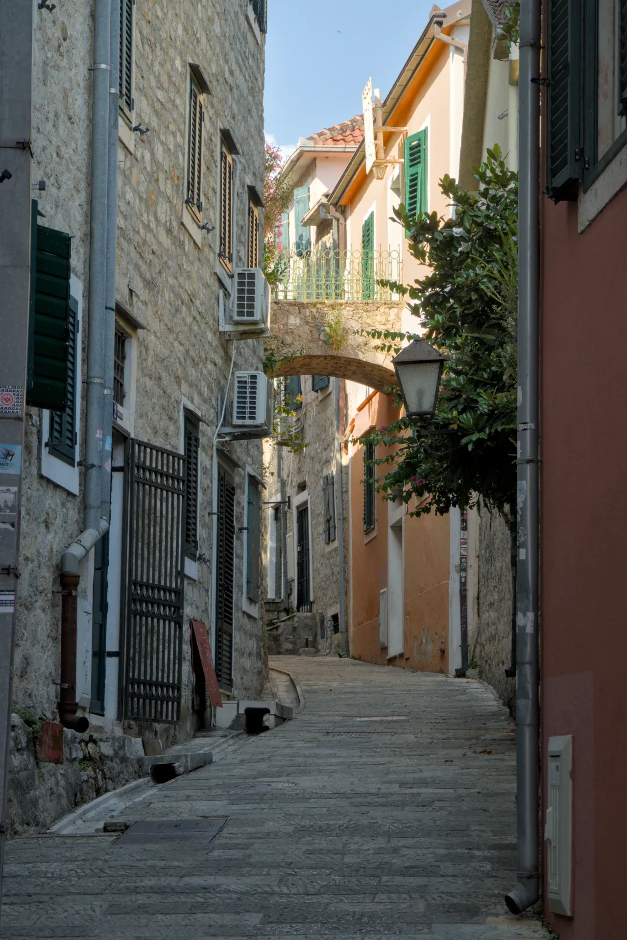 A stone alley in Herceg Novi, Montenegro, with old houses and an arch above, inviting exploration.