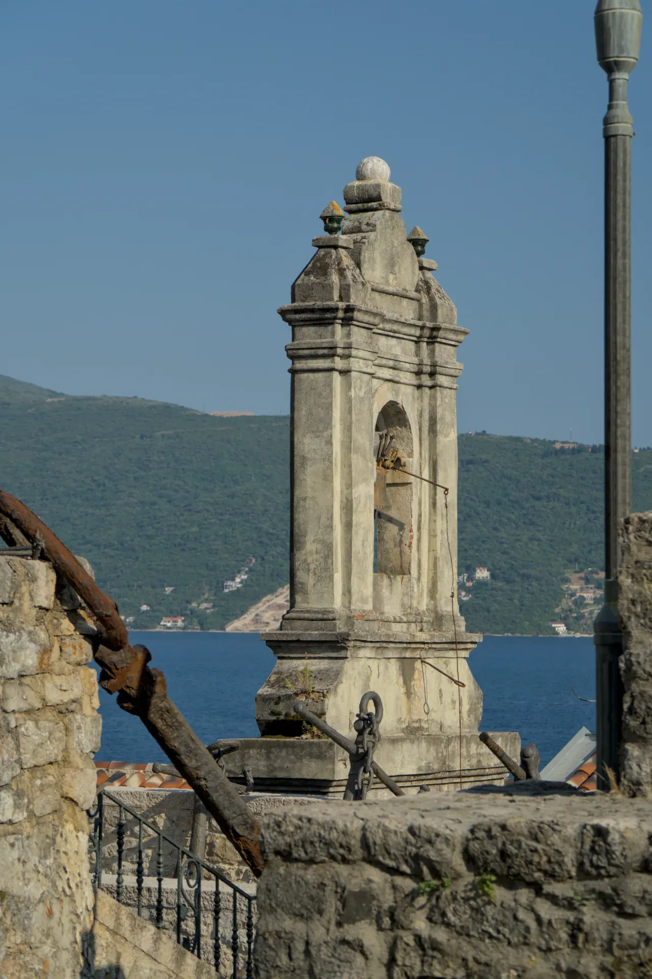 Ein verwitterter Steinglockenturm mit Blick auf das Meer in Herceg Novi, Montenegro, mit antiken Ankern.