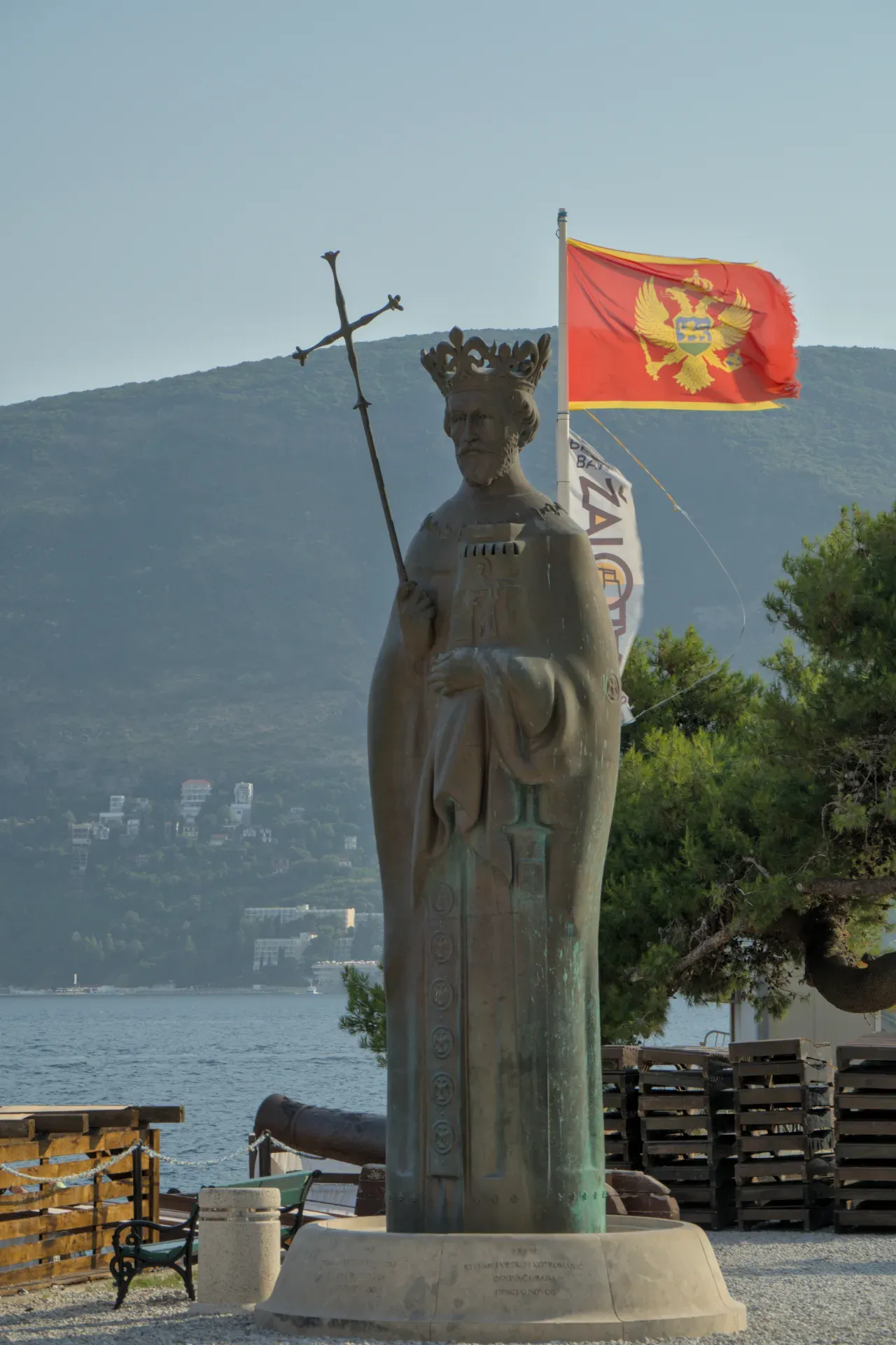 Portrait of a king's monument in Herceg Novi, Montenegro, with the state coat of arms and the sea in the background.