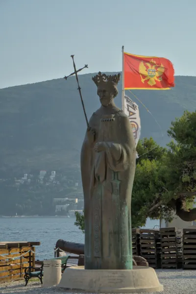 Portrait of a king's monument in Herceg Novi, Montenegro, with the state coat of arms and the sea in the background.