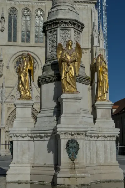 Drei goldene Engelsstatuen stehen auf einer Steinsäule vor dem monumentalen Zagreber Dom.