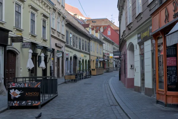 Eine schmale, gepflasterte Gasse in Zagreb mit historischen Gebäuden und Geschäften, aufgenommen im Querformat.