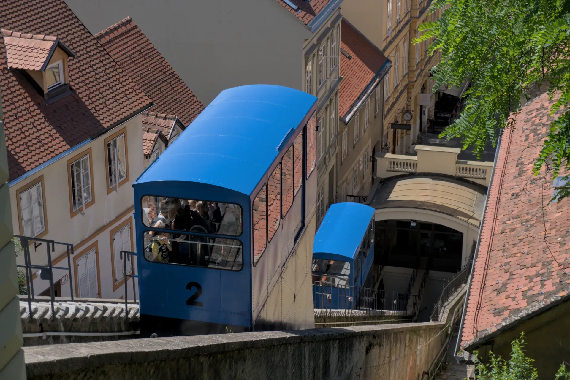 La funicolare blu di Zagabria attraversa la città in una giornata di sole, con edifici storici sullo sfondo.