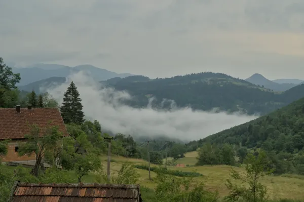 Dense fog rising in the mountains of Tara National Park, Serbia, with a brick house in the foreground.