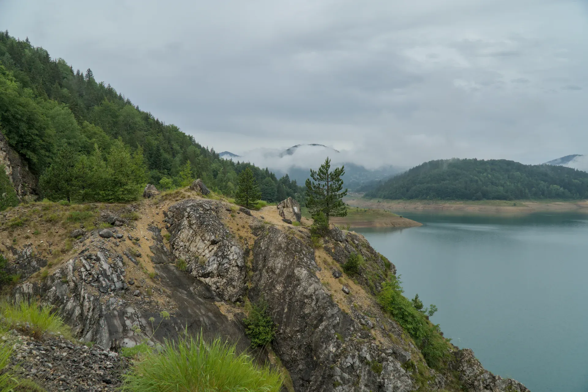 Il Lago Zaovine, circondato da ripide rocce e attraversato da lingue di nebbia, offre uno spettacolo naturale maestoso.