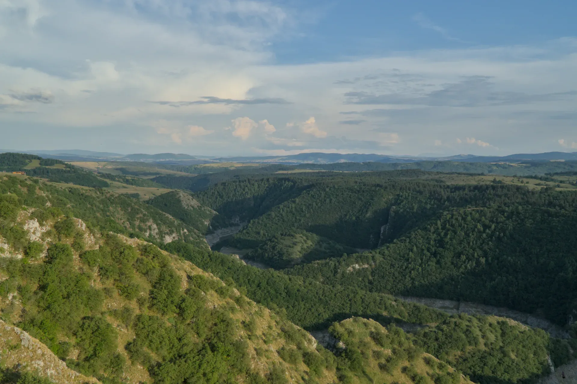 Aerial view of the Uvac River meanders in Serbia during golden hour, with rolling hills and a river.