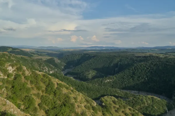 Aerial view of the Uvac River meanders in Serbia during golden hour, with rolling hills and a river.