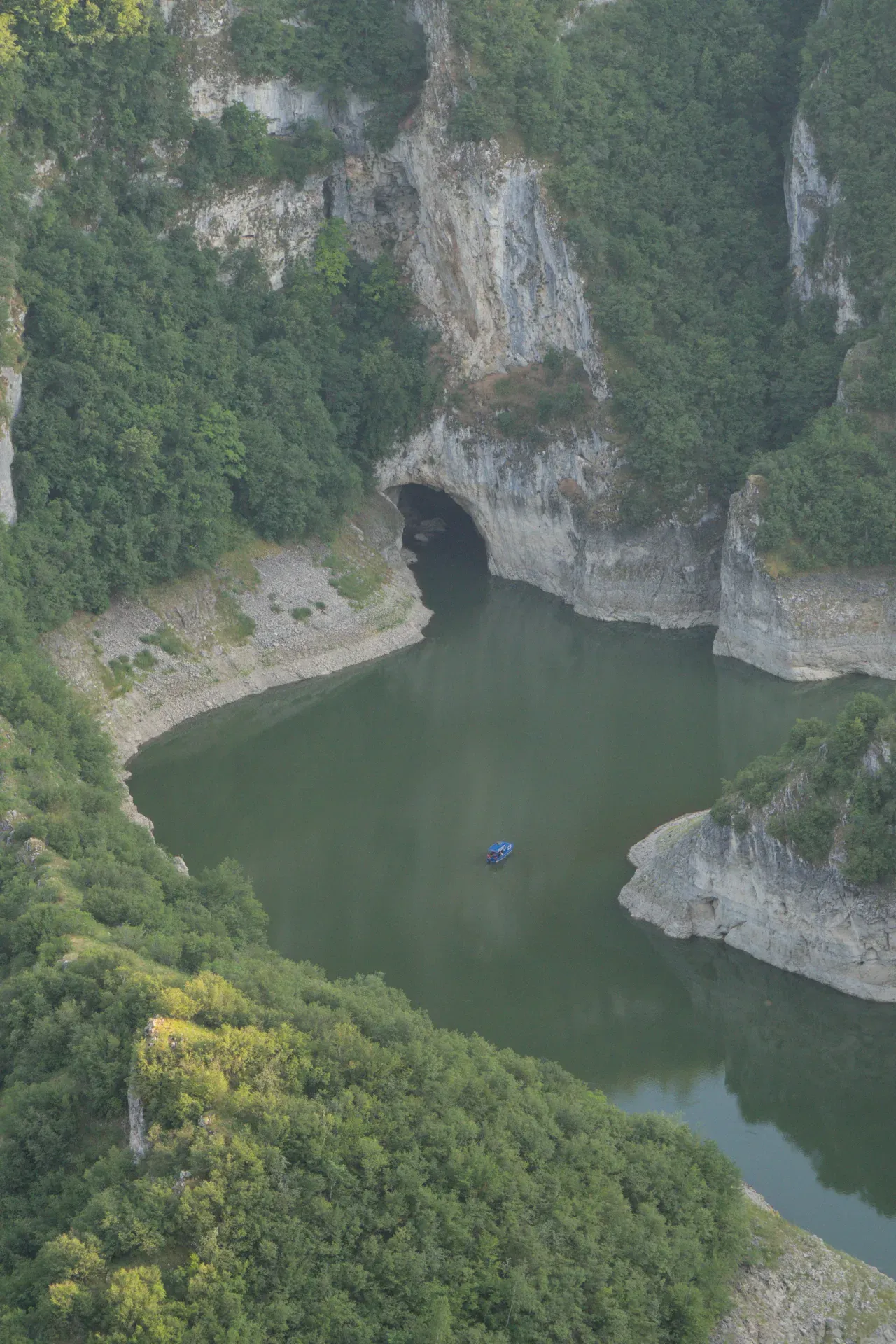A blue boat travels on the river towards Ušac Cave in Uvac Canyon, Serbia.