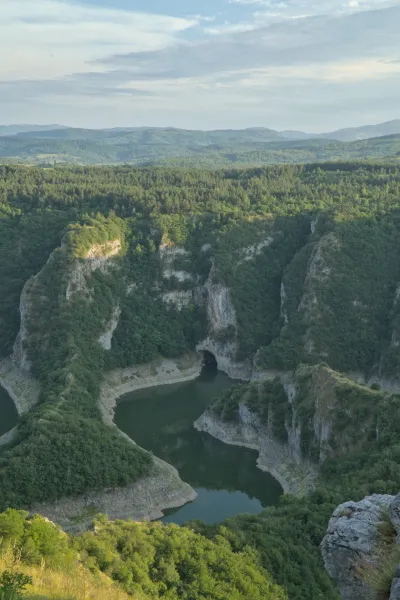 Panorama of Uvac Gorge in Serbia with a deep green valley, river, and forested slopes.