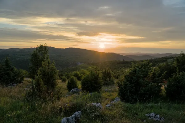 Sunset over the Uvac Valley from Mljetva Viewpoint, Serbia, with dramatic clouds and sun-drenched hills.