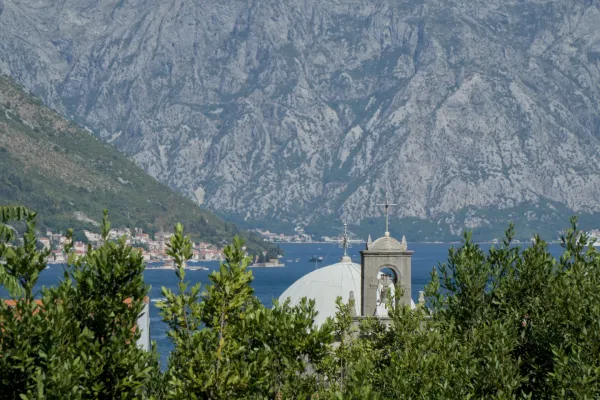 The church and the Bay of Kotor near Morini, Montenegro, with dramatic mountains in the background.